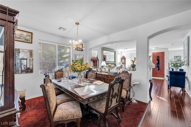 dining space featuring arched walkways, a notable chandelier, visible vents, dark wood-type flooring, and baseboards