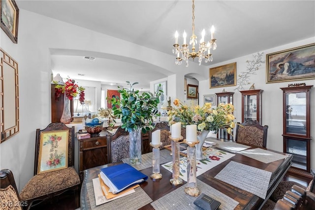 dining room with a chandelier, arched walkways, and visible vents