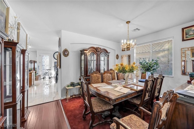 dining space featuring dark wood-type flooring, french doors, visible vents, and an inviting chandelier