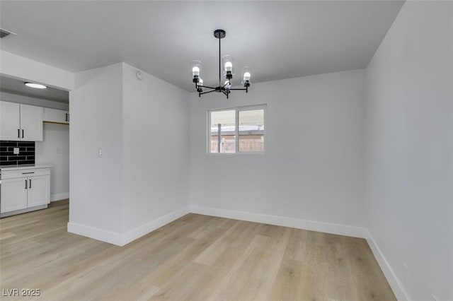 unfurnished dining area with baseboards, an inviting chandelier, and light wood-style floors