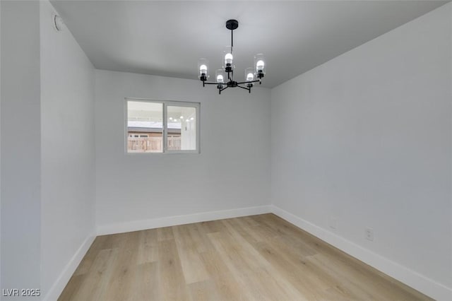 empty room with baseboards, light wood-type flooring, and a notable chandelier