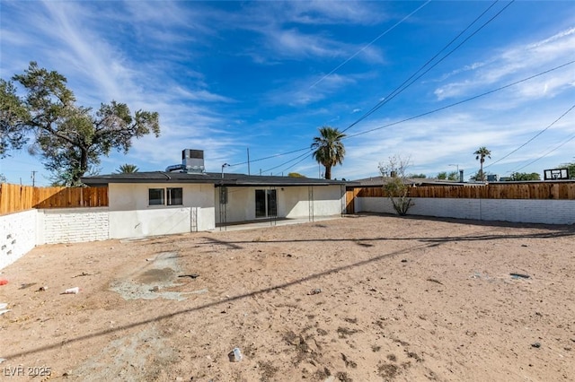 rear view of house featuring fence private yard and stucco siding