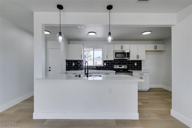 kitchen with stainless steel appliances, a sink, white cabinetry, light wood finished floors, and tasteful backsplash