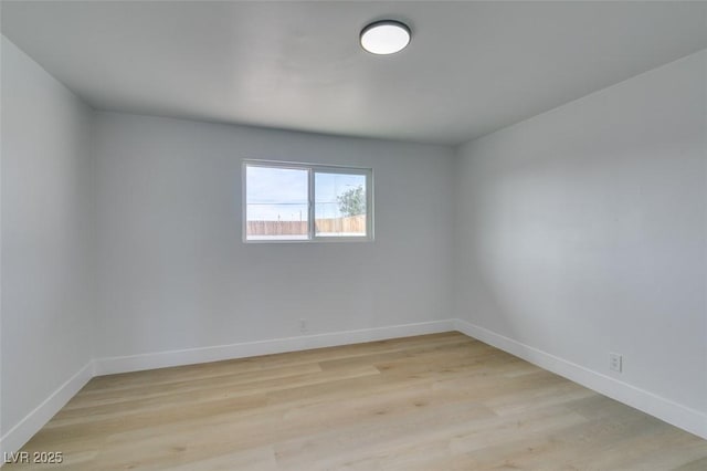 empty room featuring light wood-type flooring and baseboards