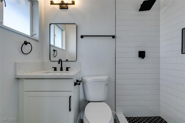 bathroom with tiled shower, vanity, and toilet