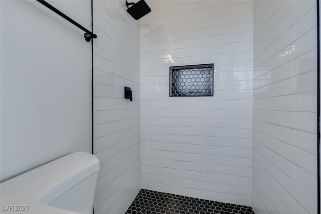 bathroom with a tile shower and toilet