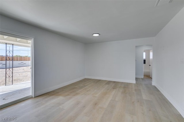 unfurnished room featuring light wood finished floors, visible vents, and baseboards