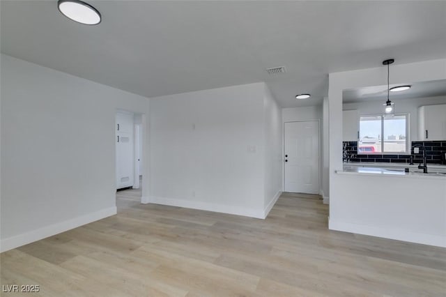 kitchen featuring light wood finished floors, tasteful backsplash, baseboards, and light countertops