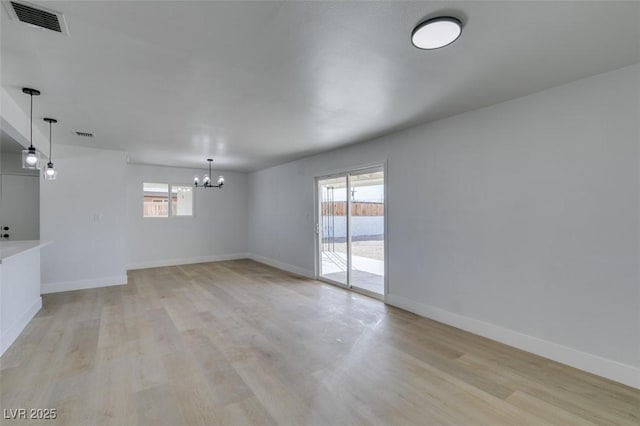unfurnished room with visible vents, plenty of natural light, light wood-style flooring, and an inviting chandelier