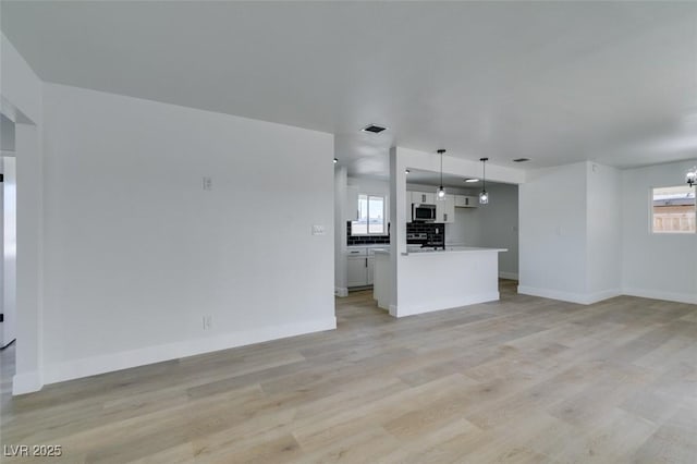 unfurnished living room with light wood finished floors, baseboards, and visible vents
