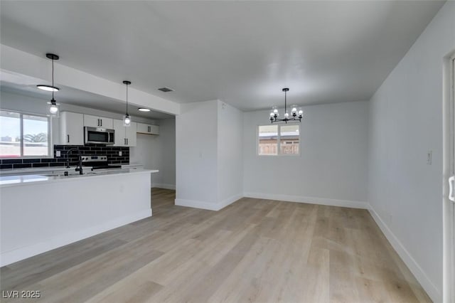 kitchen featuring a healthy amount of sunlight, light wood finished floors, appliances with stainless steel finishes, and backsplash