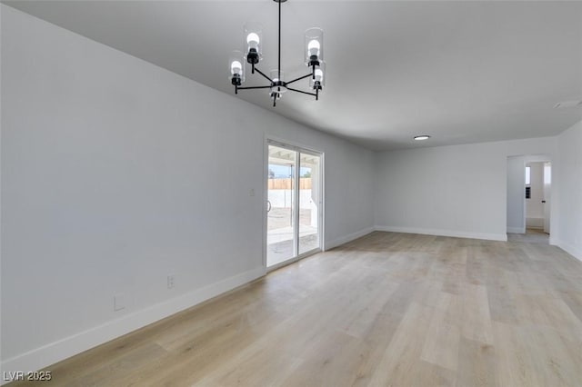 unfurnished room featuring light wood finished floors, baseboards, and a chandelier