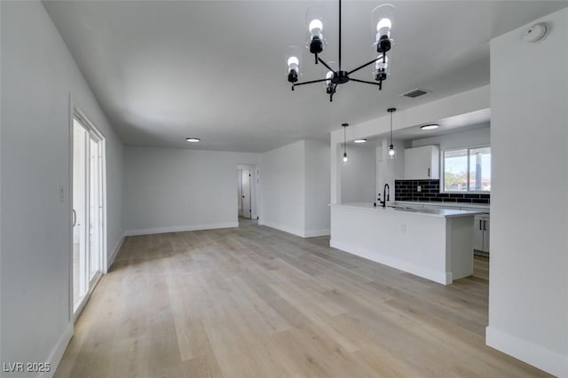 kitchen featuring light countertops, visible vents, decorative backsplash, light wood-style floors, and baseboards
