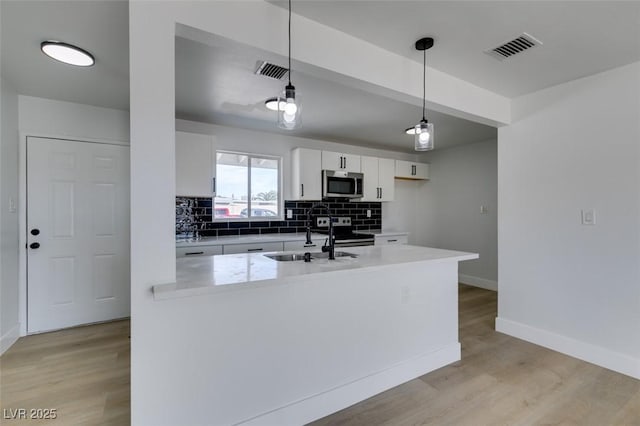 kitchen with stainless steel appliances, tasteful backsplash, visible vents, and white cabinetry
