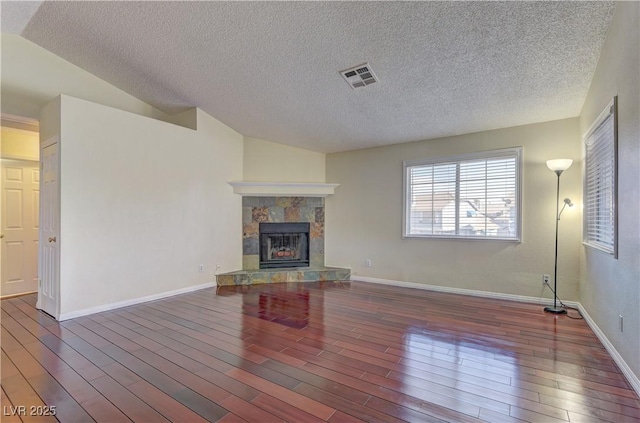 unfurnished living room with visible vents, a stone fireplace, and wood finished floors