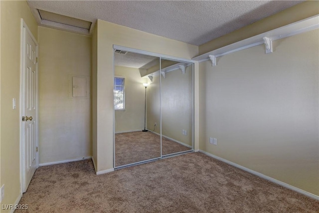 unfurnished bedroom with baseboards, visible vents, a textured ceiling, carpet flooring, and a closet