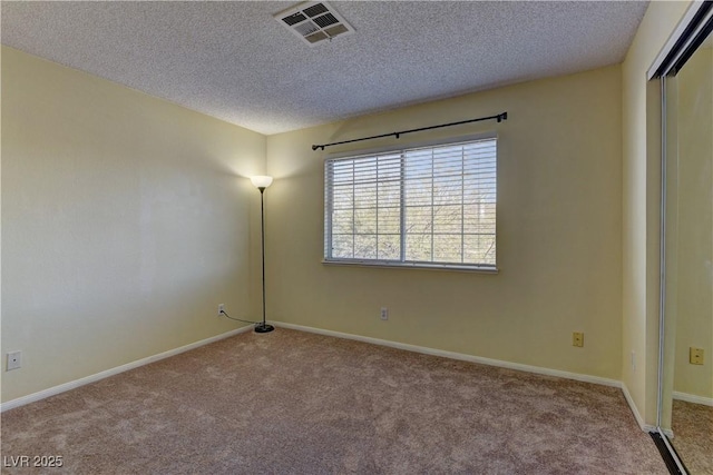 carpeted empty room with baseboards, visible vents, and a textured ceiling