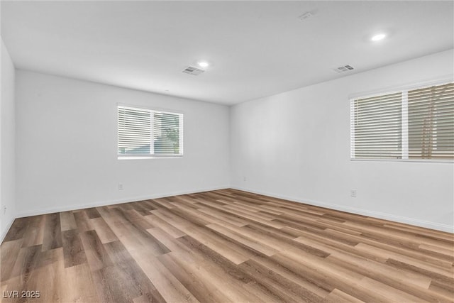 spare room with baseboards, visible vents, and wood finished floors