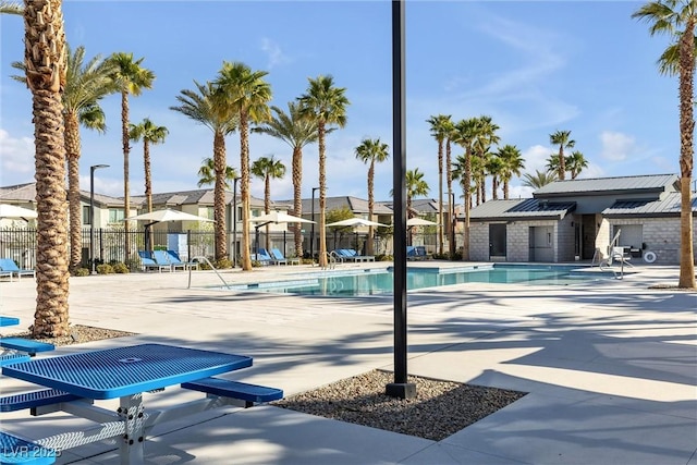 community pool with a residential view, a patio area, and fence