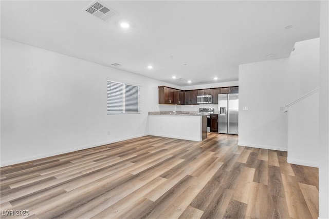 kitchen featuring stainless steel appliances, light countertops, visible vents, open floor plan, and dark brown cabinets