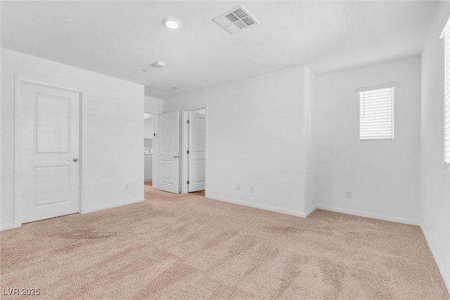 empty room featuring baseboards, visible vents, and light colored carpet