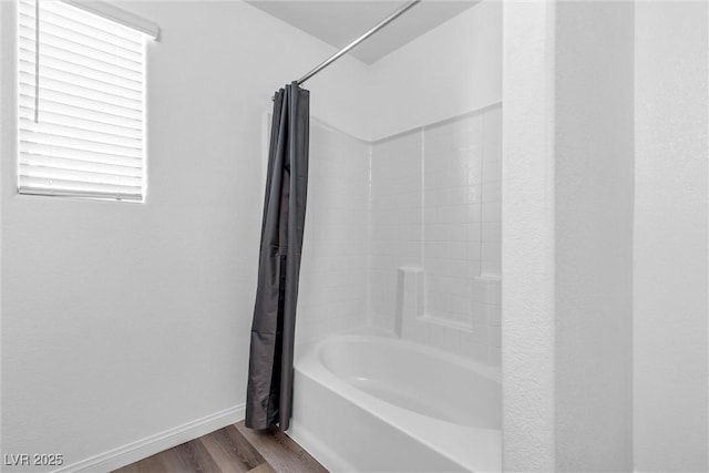 bathroom with shower / bath combo, wood finished floors, and baseboards