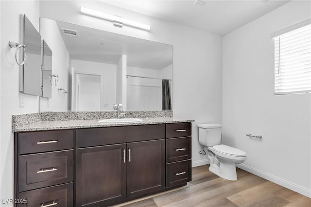 bathroom with visible vents, toilet, vanity, wood finished floors, and baseboards