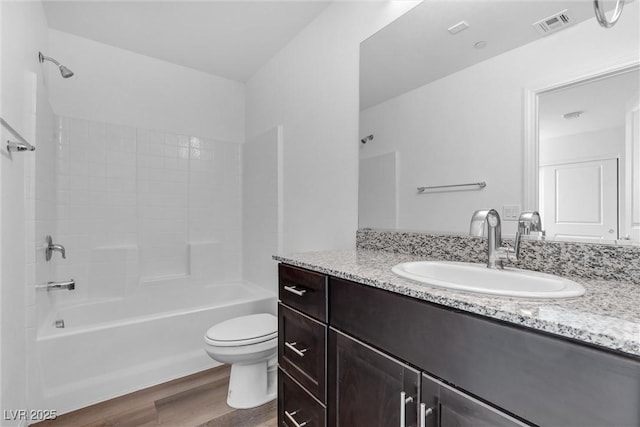 bathroom with bathtub / shower combination, toilet, wood finished floors, visible vents, and vanity