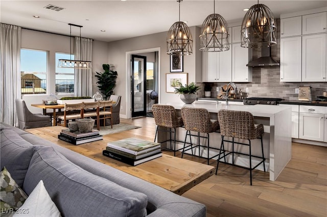 living room featuring light wood-style floors, recessed lighting, visible vents, and baseboards