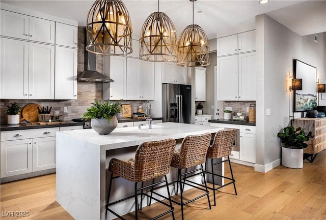 kitchen featuring a sink, light wood-style flooring, a kitchen bar, and high end fridge