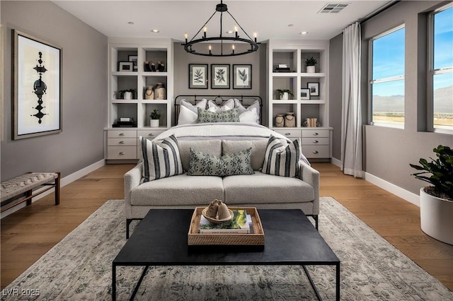 bedroom with light wood finished floors, visible vents, and baseboards