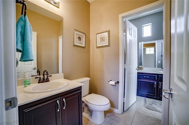 bathroom featuring tile patterned flooring, baseboards, vanity, and toilet