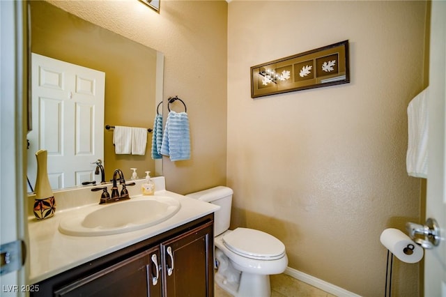 half bathroom with vanity, toilet, and baseboards