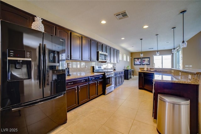 kitchen featuring hanging light fixtures, visible vents, appliances with stainless steel finishes, and dark brown cabinets