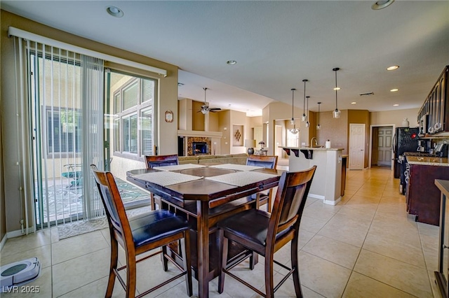 dining area with light tile patterned floors, ceiling fan, recessed lighting, baseboards, and a brick fireplace