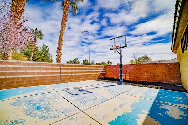 view of basketball court with basketball hoop and a fenced backyard