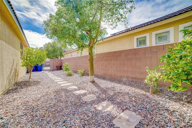 view of yard with a fenced backyard and a gate