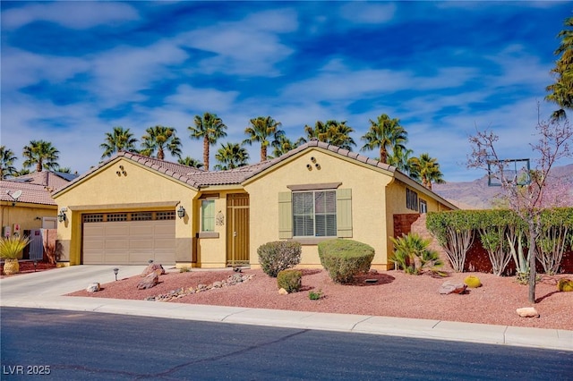 mediterranean / spanish house featuring a garage, a tile roof, concrete driveway, and stucco siding