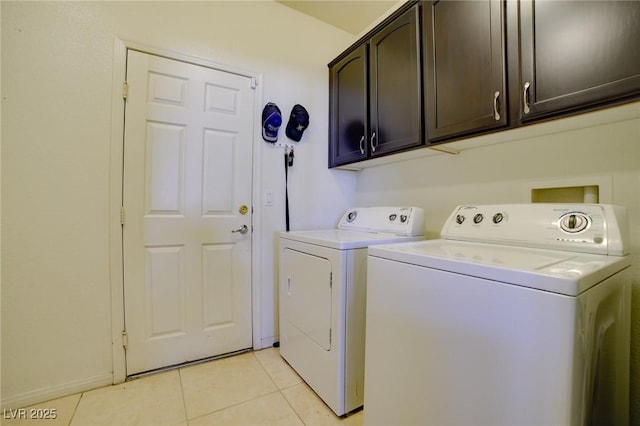 laundry area with light tile patterned floors, separate washer and dryer, and cabinet space