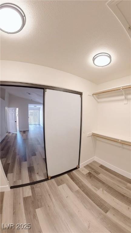 walk in closet with light wood finished floors