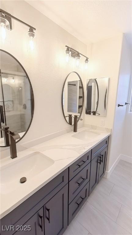 full bath with a sink, baseboards, and double vanity