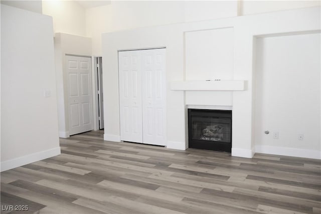 1624 N Torrey Pines Dr Unit 101, Las Vegas, NV 89108 - unfurnished living room featuring wood finished floors, a fireplace, baseboards, and a towering ceiling