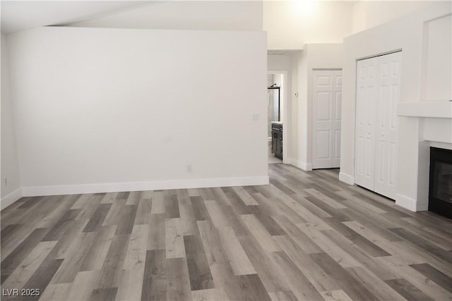 1624 N Torrey Pines Dr Unit 101, Las Vegas, NV 89108 - unfurnished living room featuring a tiled fireplace, wood finished floors, baseboards, and high vaulted ceiling