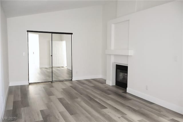1624 N Torrey Pines Dr Unit 101, Las Vegas, NV 89108 - unfurnished living room with a glass covered fireplace, wood finished floors, and baseboards