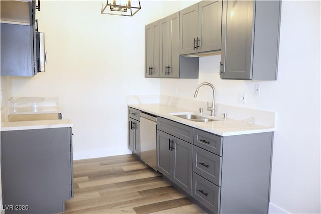 1624 N Torrey Pines Dr Unit 101, Las Vegas, NV 89108 - kitchen with gray cabinetry, a sink, dishwasher, light wood-style flooring, and light countertops