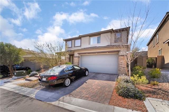 view of front facade with a gate, an attached garage, stucco siding, stone siding, and decorative driveway