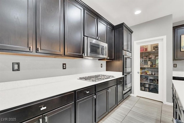 kitchen with baseboards, stainless steel appliances, light countertops, and recessed lighting