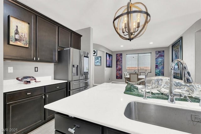 kitchen with decorative light fixtures, light countertops, a sink, a chandelier, and stainless steel fridge with ice dispenser