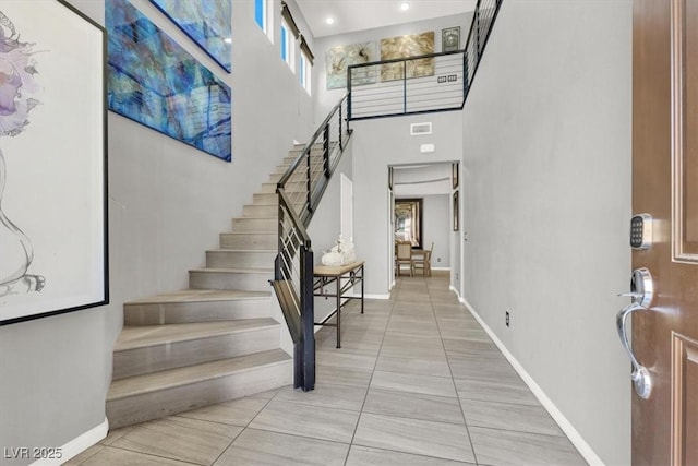 entryway with a high ceiling, stairway, visible vents, and baseboards