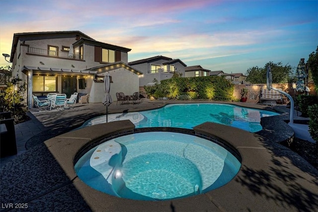 view of swimming pool with a patio area, a pool with connected hot tub, and fence